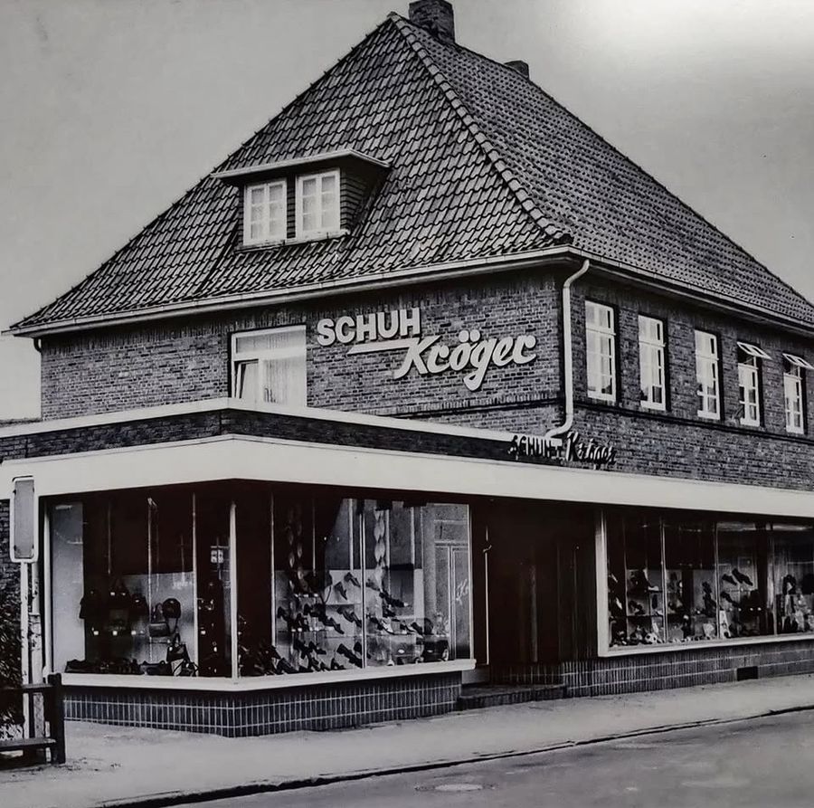 Schwarzweißfoto von 1974: das Eckgebäude mit dem Schriftzug „Schuh Kröger“ und großen Schaufenstern voller Schuhe.
